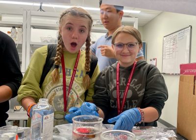 Students with gloves on smiling at the camera