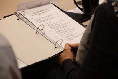 A three-ring binder being head by an individual and read.