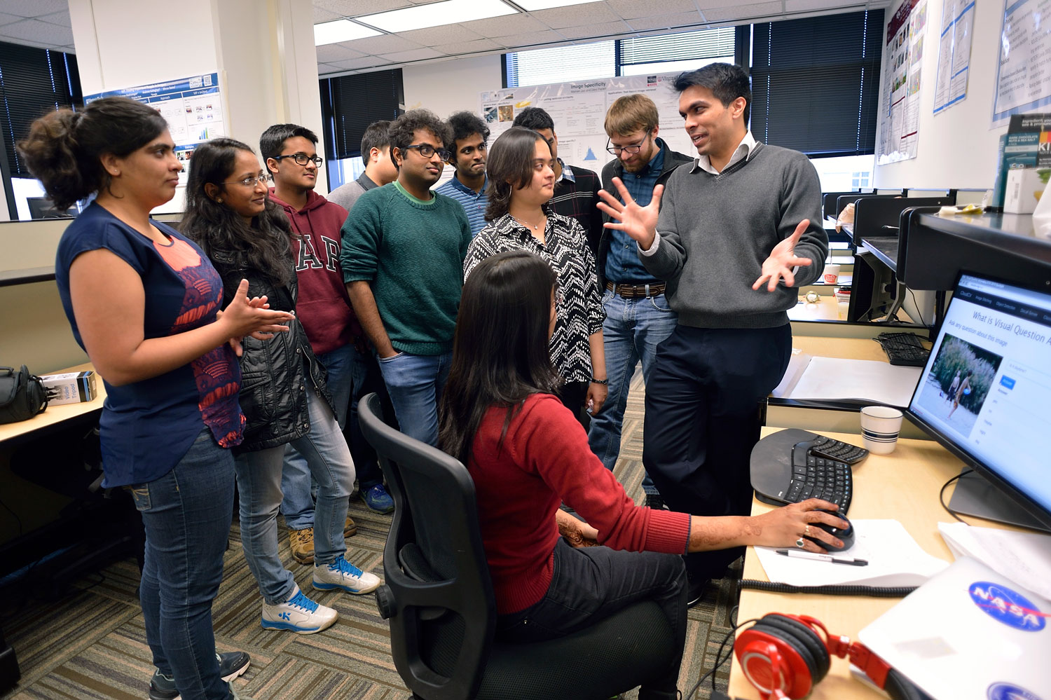 northern-virginia-graduate-programs Graduate students gather around a faculty member and a computer on a desk.