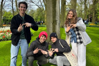 Four students in a park throwing the VT hand-sign.