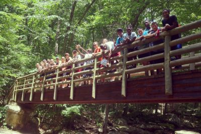 STEP students on a walking bridge in the woods on a field trip.
