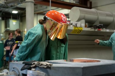 Two girls looking at liquid metal at foundry.