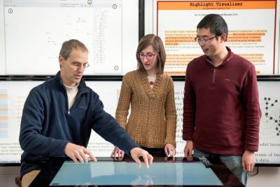 Researchers looking at a big touch screen below them
