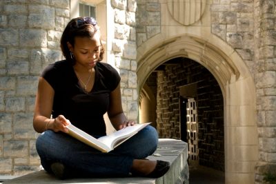 Student reading in front of arch