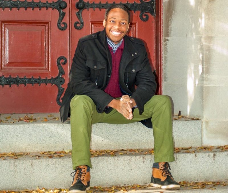 Quincy Brooks sitting on the steps in front of a red door.