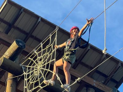 Student reaching for a rope on the ropes course