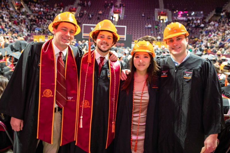 Undergraduate students pose for a groups shot with hard hats at fall 2022 commencement.