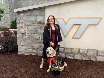 Abigail Bock with her service dog, Duke, in front of Lane Stadium before graduation.