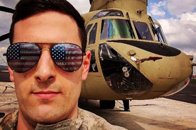 Anthony Daly poses with American flag sunglasses in front of a Chinook helicopter