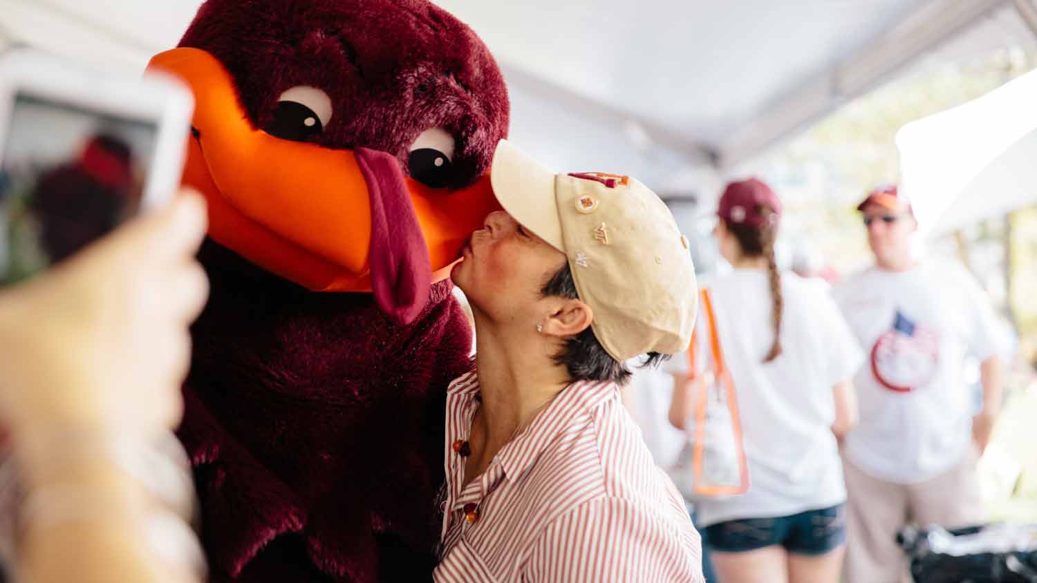 A women kissing the Hokie Bird at an alumni event.