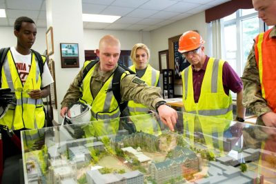 Meyer's-Lawson students look over a table with a 3D model of the new Virginia Tech Cadet dorms.