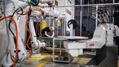 A student working in a lab with large robotic arms. 