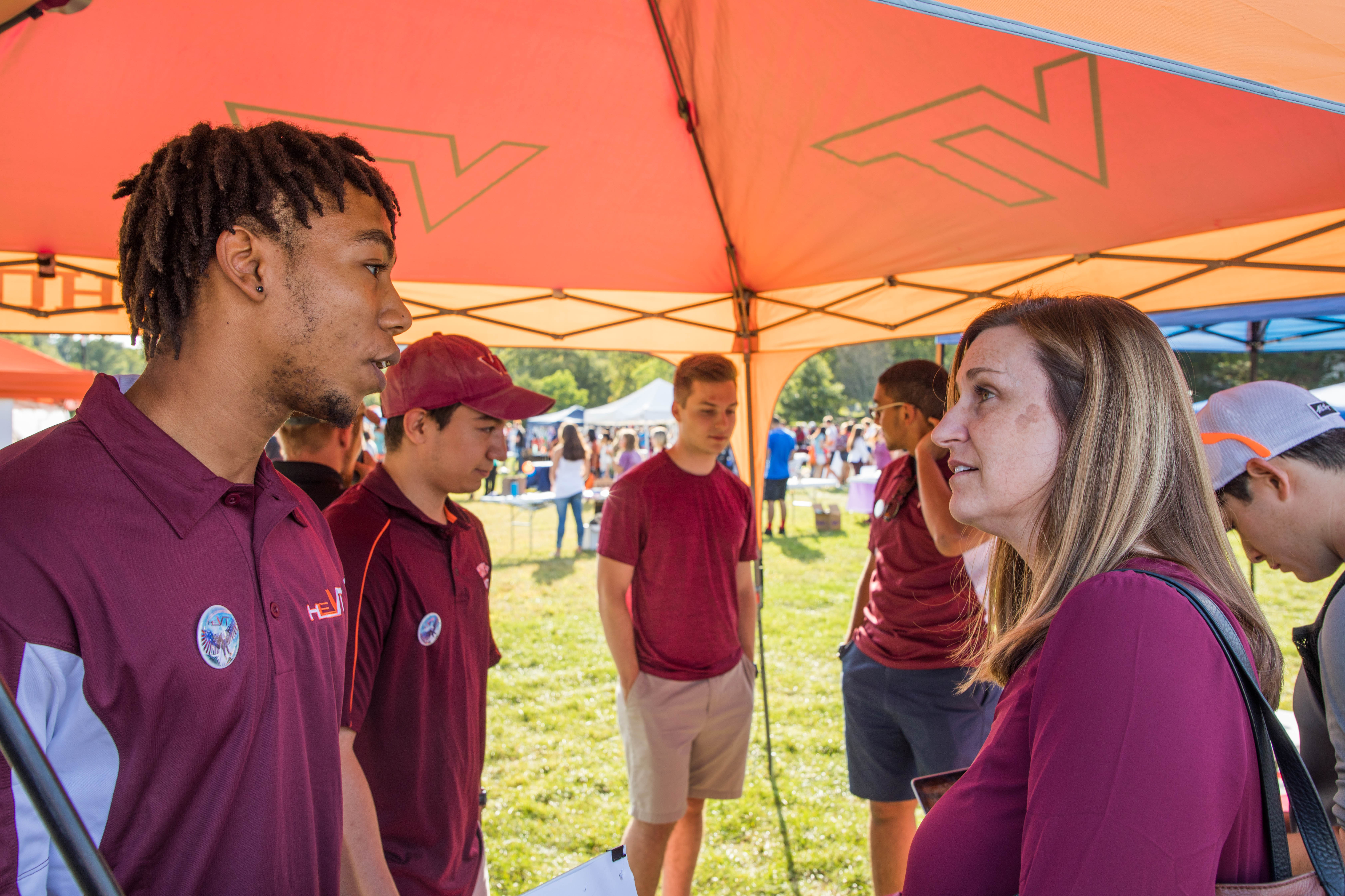 A student speaks with Dean Julia Ross under a tent on the Drillfield of Virginia Tech's campus.