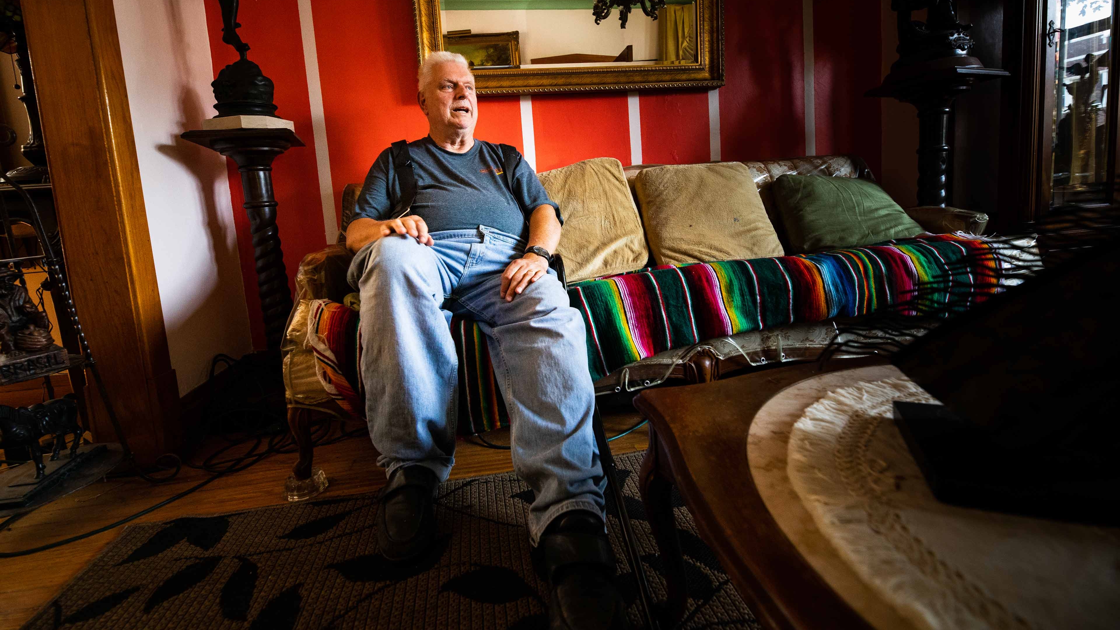 An elderly Cicero IL resident sits on the couch his colorful living room.