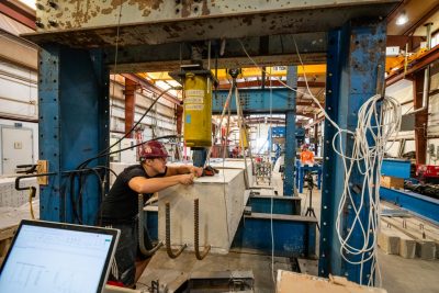 A student testing a concrete beam in the Structures Lab.