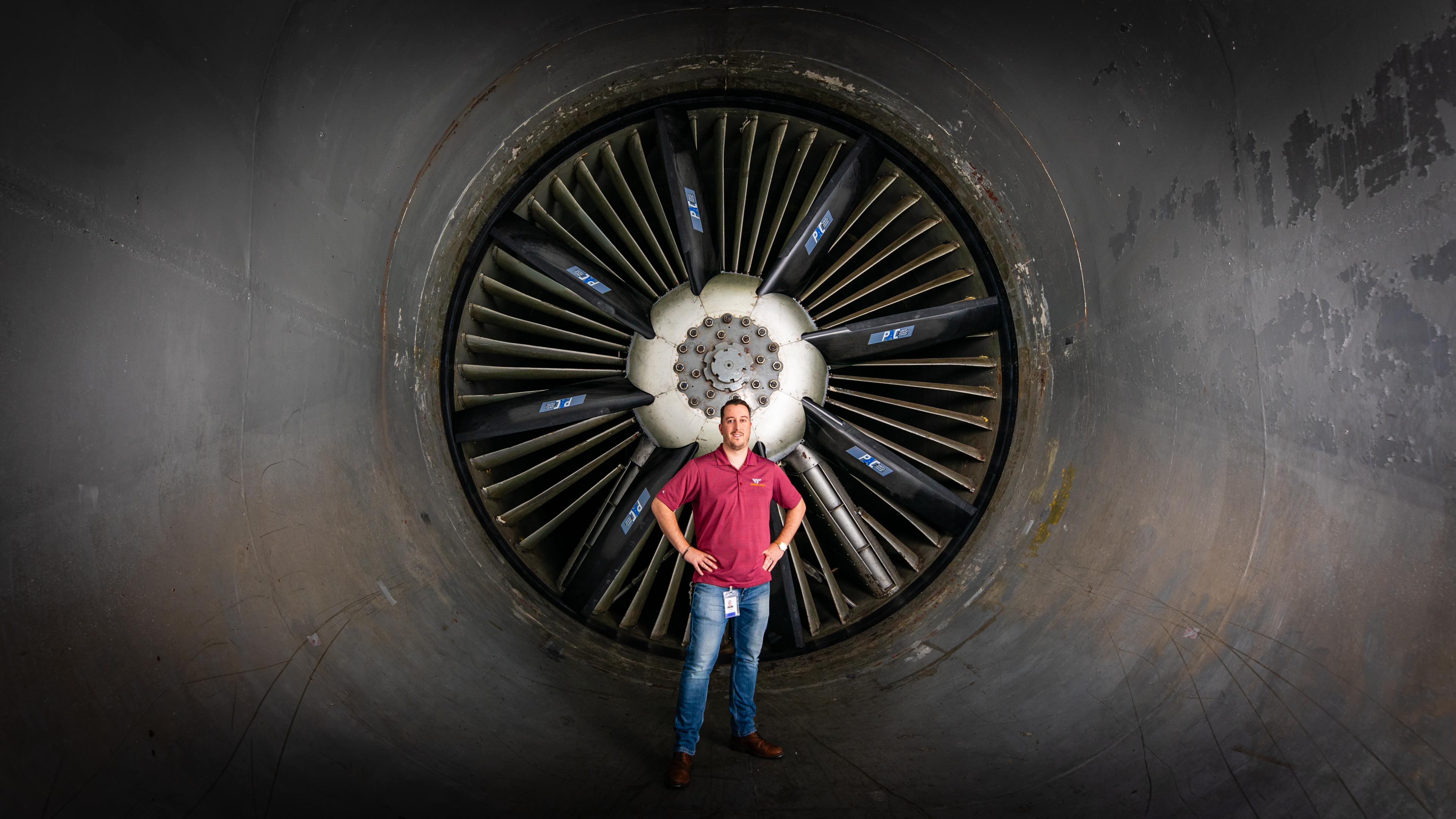 An alumni stands in front of the fan in the wind tunnel.