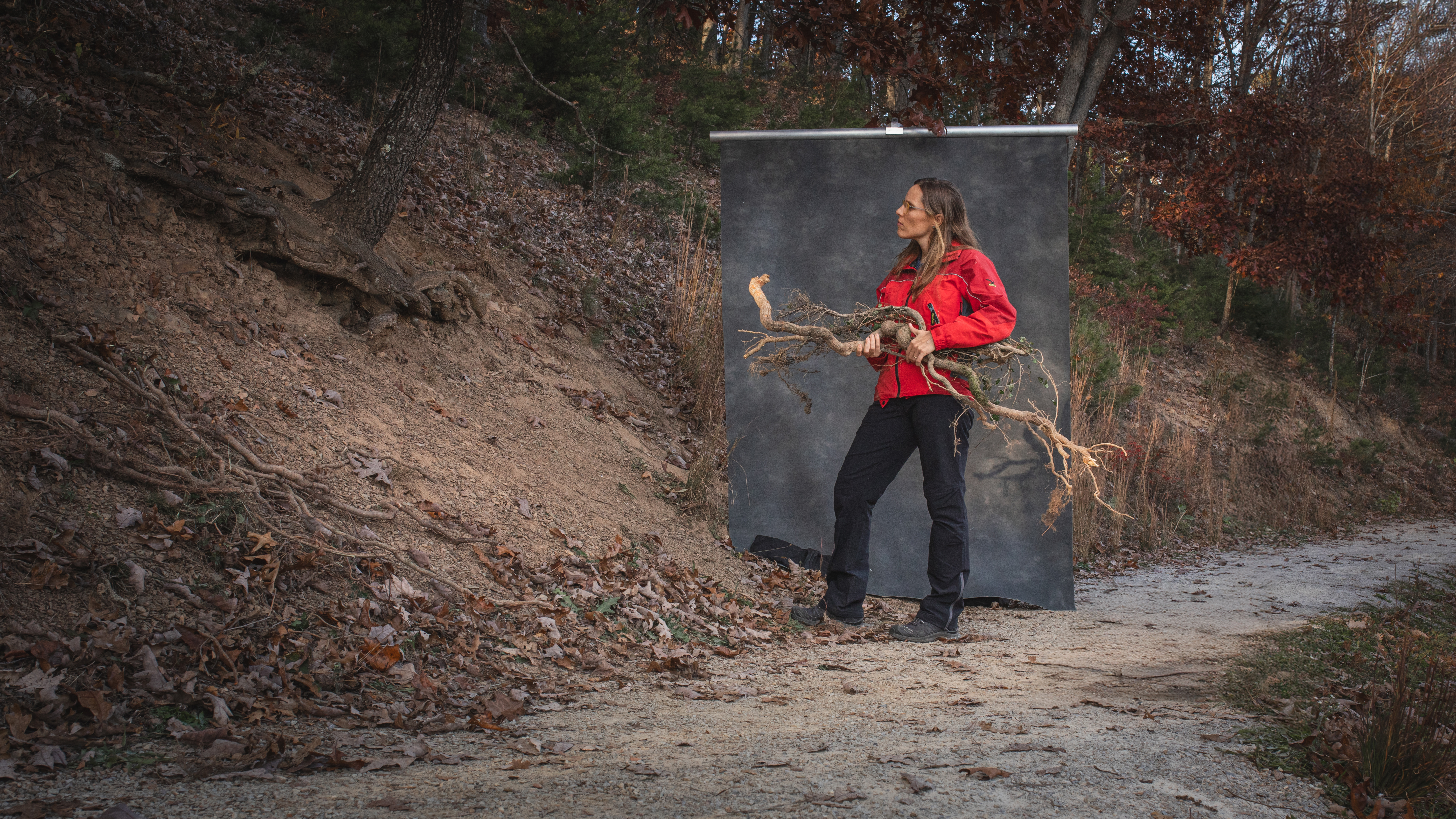 Alba Yerro-Colom stands by a washed out path side, holding a bundle of roots.