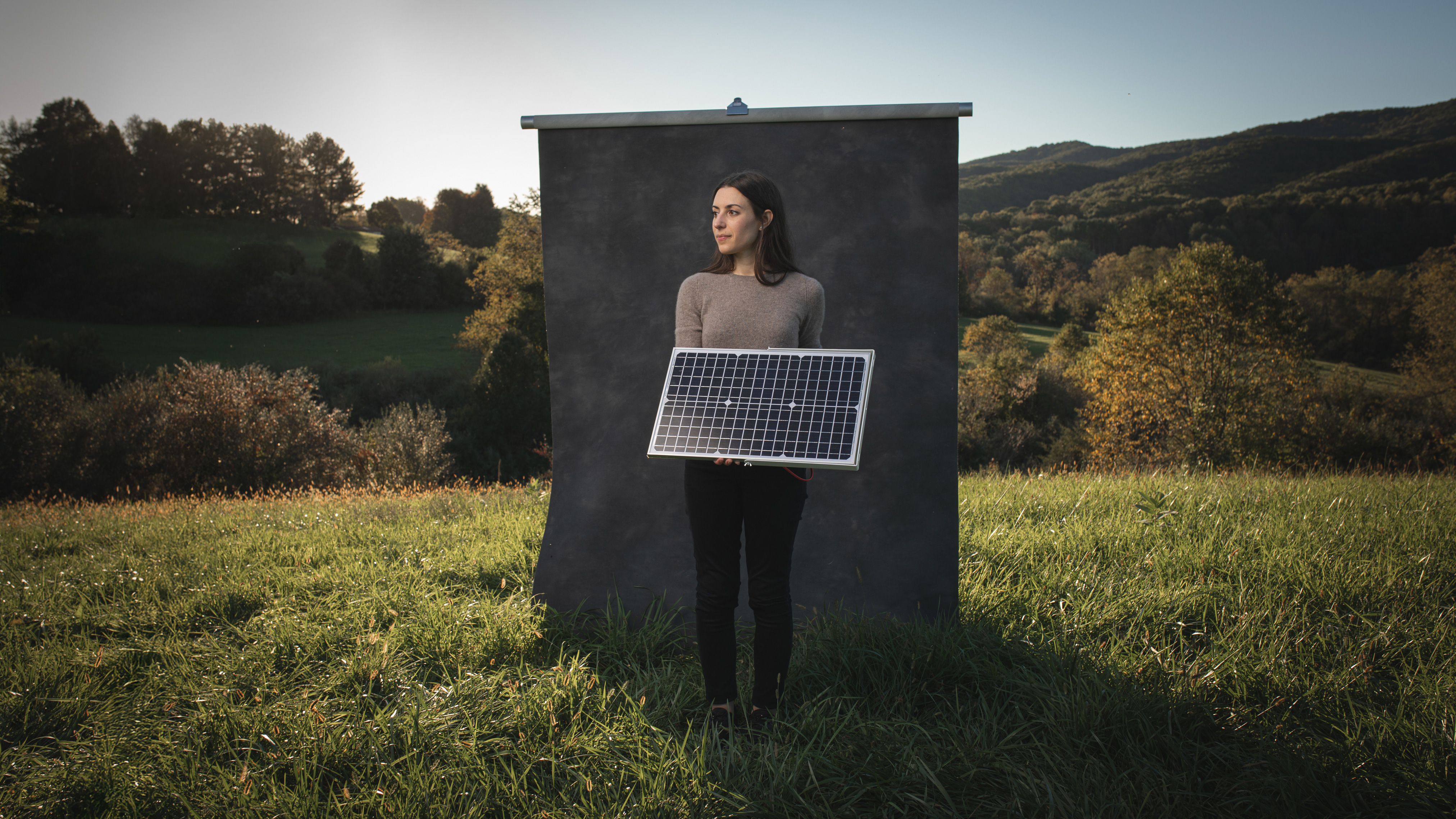 Christinia Dimarino poses in a filed with a solar panel in her arms