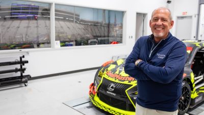 Davide Wilson of TRD poses in front of a race car in a four post testing room.