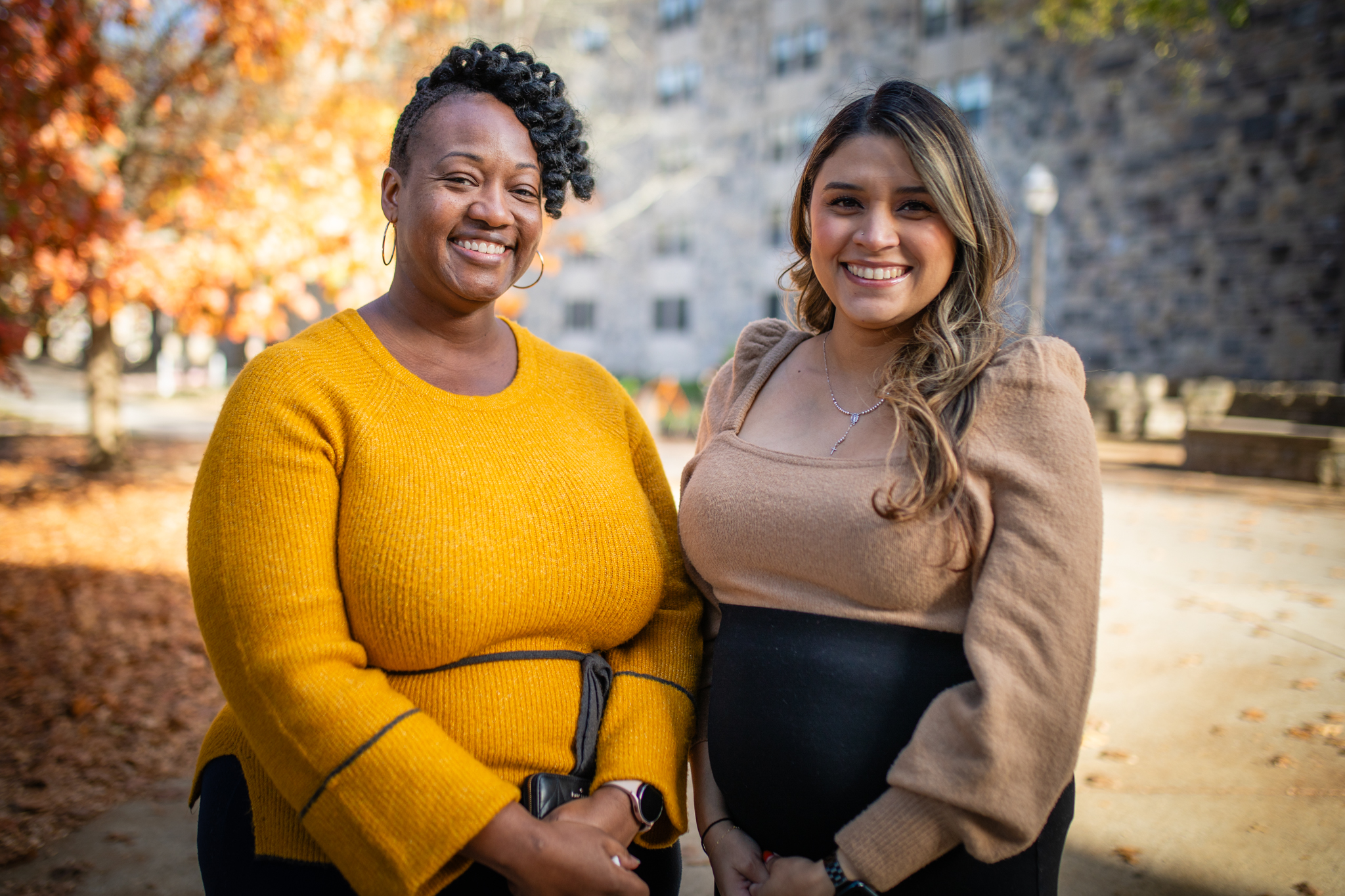 Deanna Katey and Jazmin Becerra Montaño pose together outside in the autumn on campus.