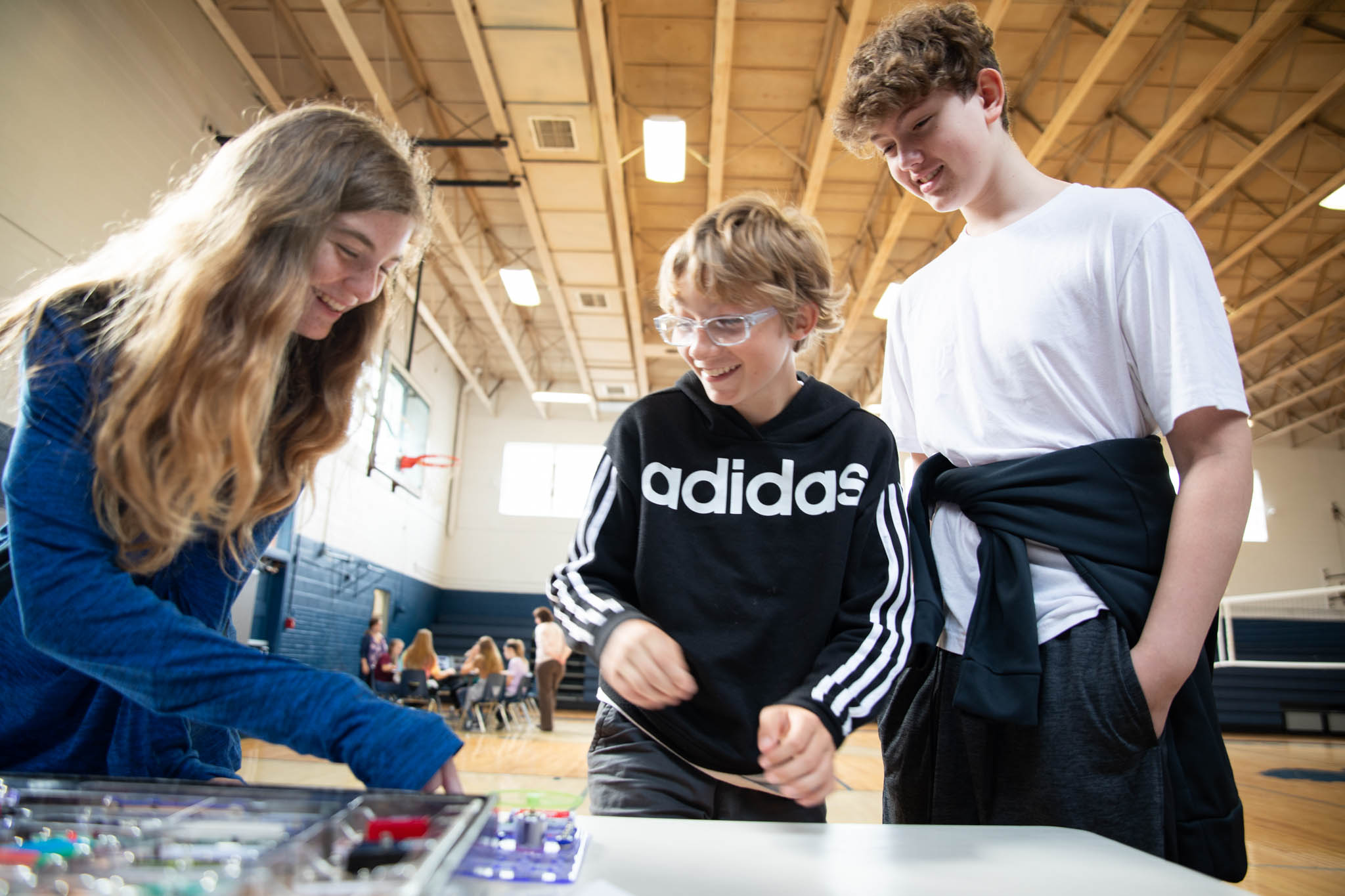 Three students work on an electrical circuit board kit and laugh.