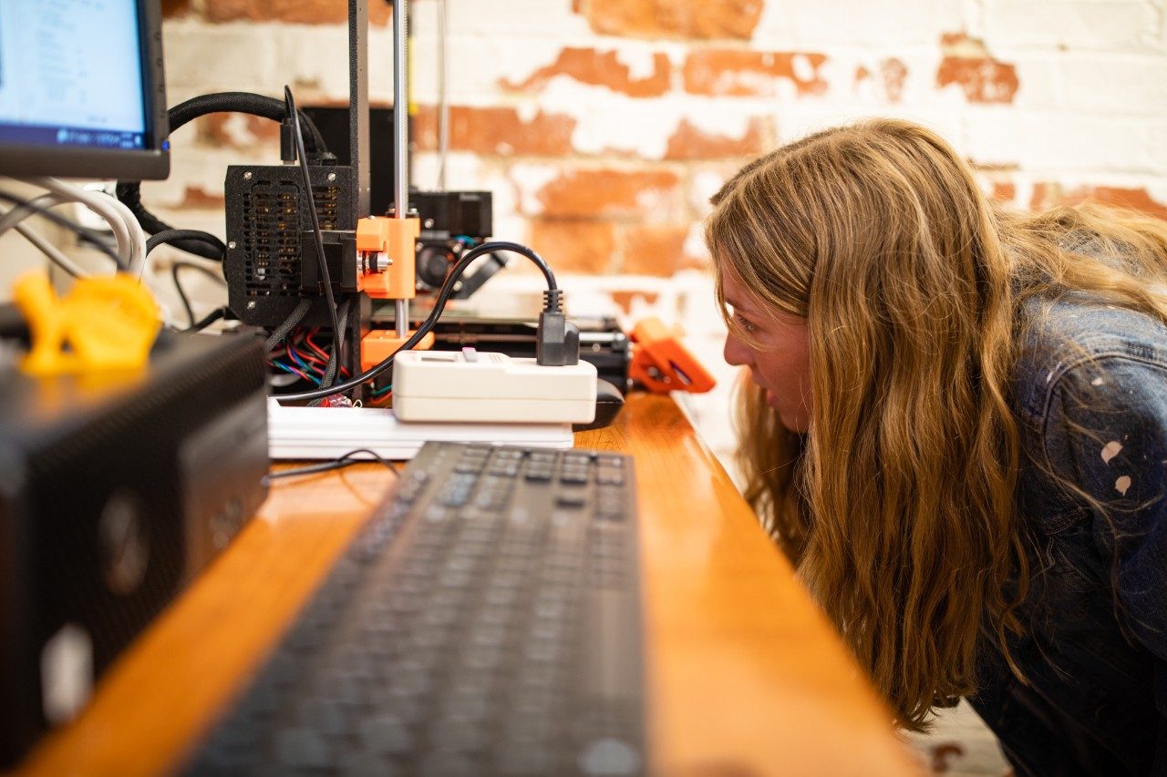 A student looking at a 3D printer.