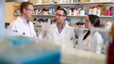 Three researchers in a lab having a discussion.