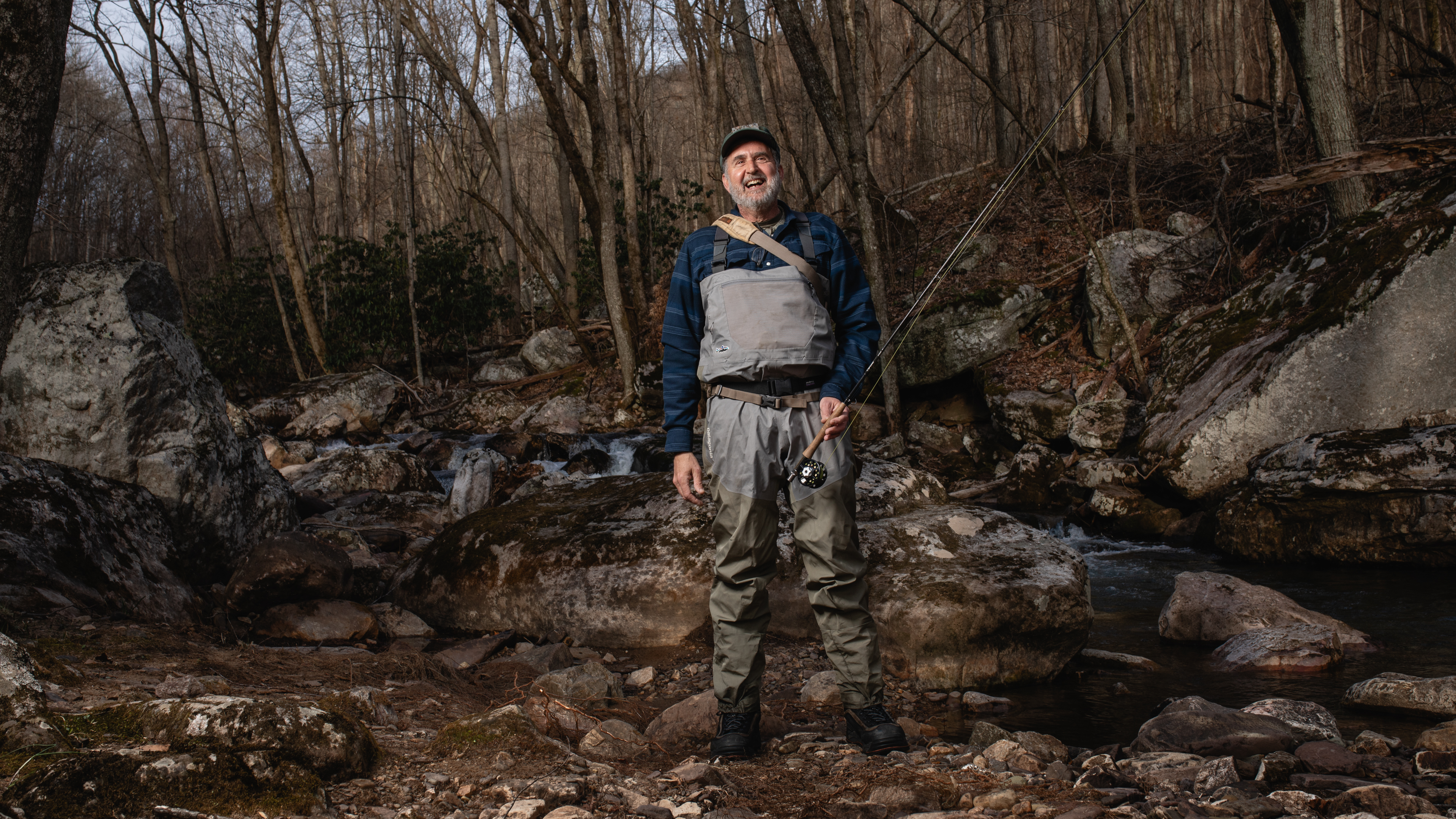 Angelino Biviano in fly fishing gear standing in the wood by a small stream.