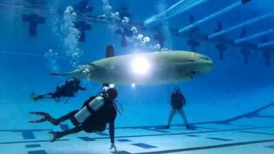 Underwater shot of the human powered sub team with the sub in a pool.