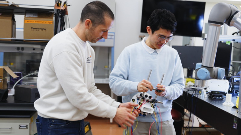 Thomas Lu in front of lab machinery. 
