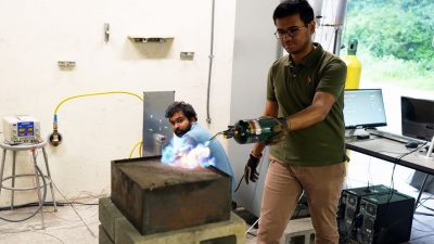 (Left to right) Researcher Manjunath Parameswaran adjusts gas flow while colleague Mehran Islam lights the flame in the Extreme Environments and Materials Lab.