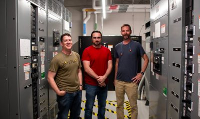  three engineers stand in a data center.