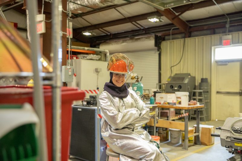 student poses in protective equipment in foundry lab.