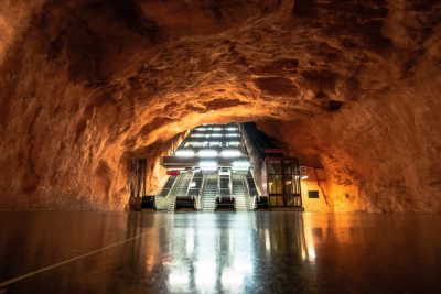 Escalators rise inside a well-lit cave, above a polished concrete floor.