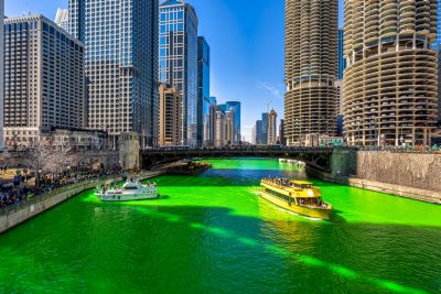 Chicago building and cityscape on Saint Patrick's day around Chicago river walk with green color dyeing river in Chicago. People dressed in green are celebrating on boats and at the river's edge.