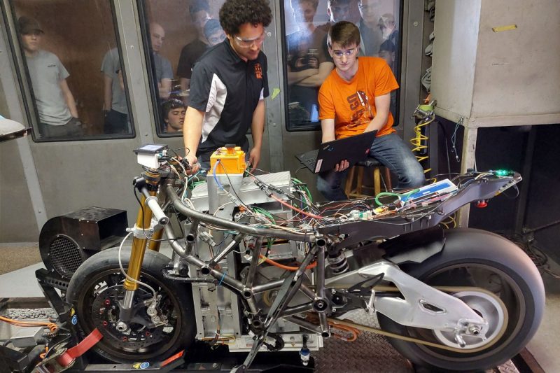 Two team members works on the Bolt motorcycle.