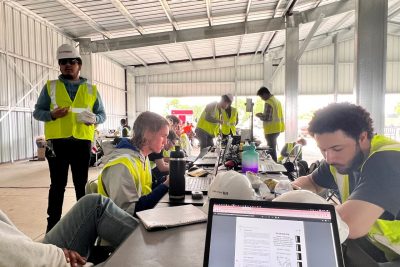 Team members work inside on laptops.