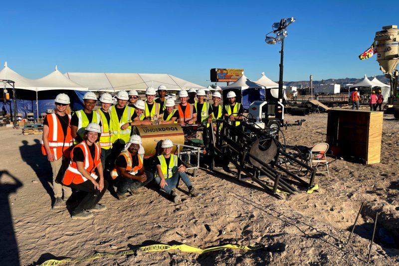 The team gathers around the digging machine for a photo.
