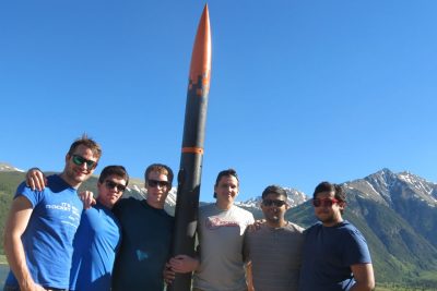 Team members in a group shot with a rocket.