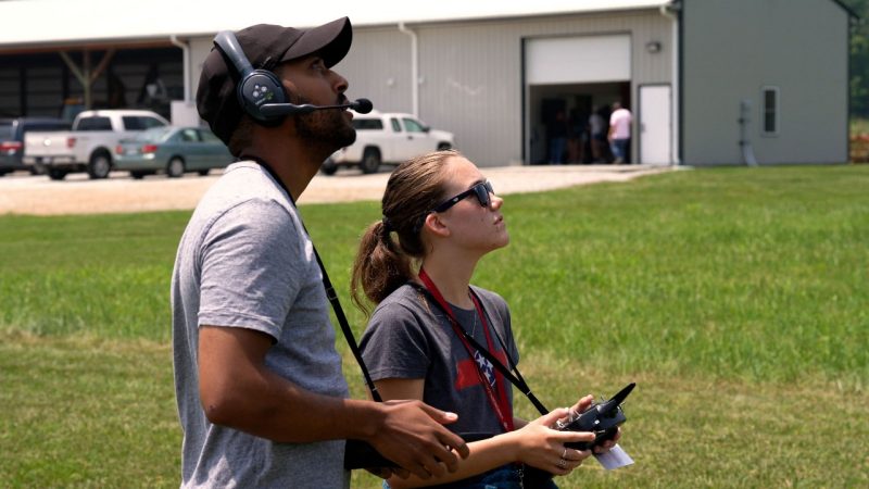 Student working with instructor using a remote control to fly a drone