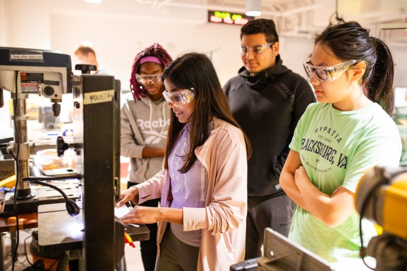 Students learning to use a drill press in the Invents Lab.