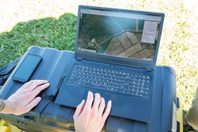 Hands working on a laptop that is displaying drone aerial footage. 