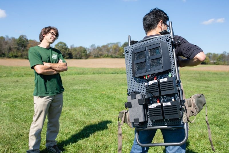 A student putting on a backpack for tracking drones.