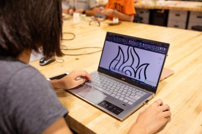A student making a line art design on a laptop.