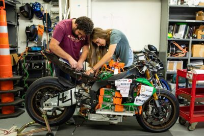 Two students working an electric motorcycle in the Ware Lab.