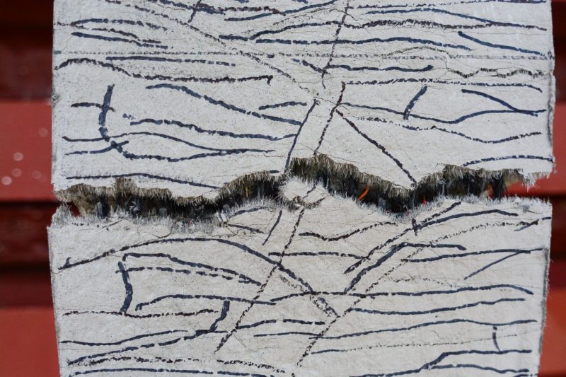 Cracked concrete showing reinforcing fibers.