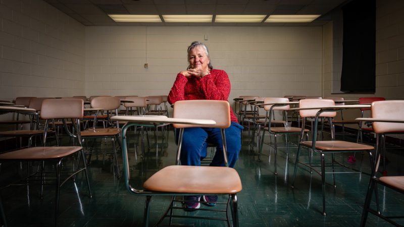 An alumni sits alone in an old classroom.