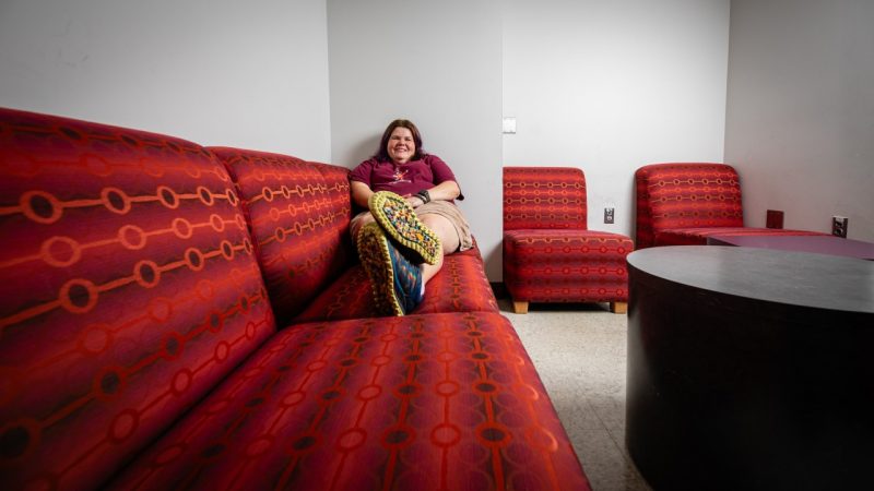 An alumni sits on a sofa in an old break room.