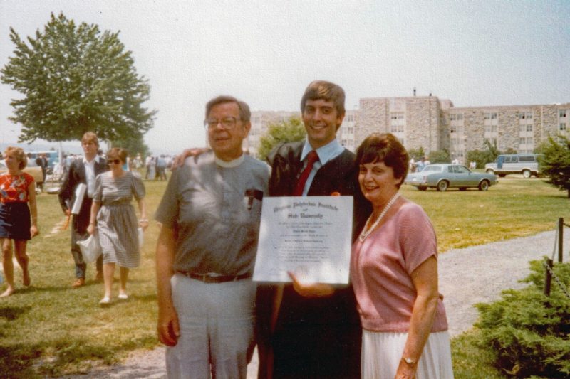 Tom Taylor with his parents, displaying his diploma a commencement.