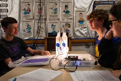 Young students works on a project with two glowing water bottles.